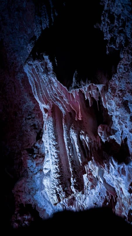 Coulées de calcite bleutées figées dans la nuit de la grotte